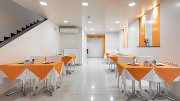 Un salón de conferencias con mesas dispuestas para reuniones, equipado con sillas y una pizarra.