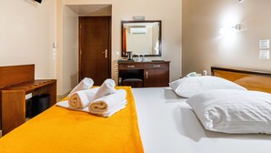 Habitación de hotel con cama, cabecera de madera, escritorio, silla, espejo y puerta al baño.