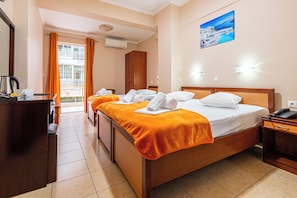 Habitación de hotel con dos camas, un escritorio, una silla, un teléfono y un cuadro en la pared.