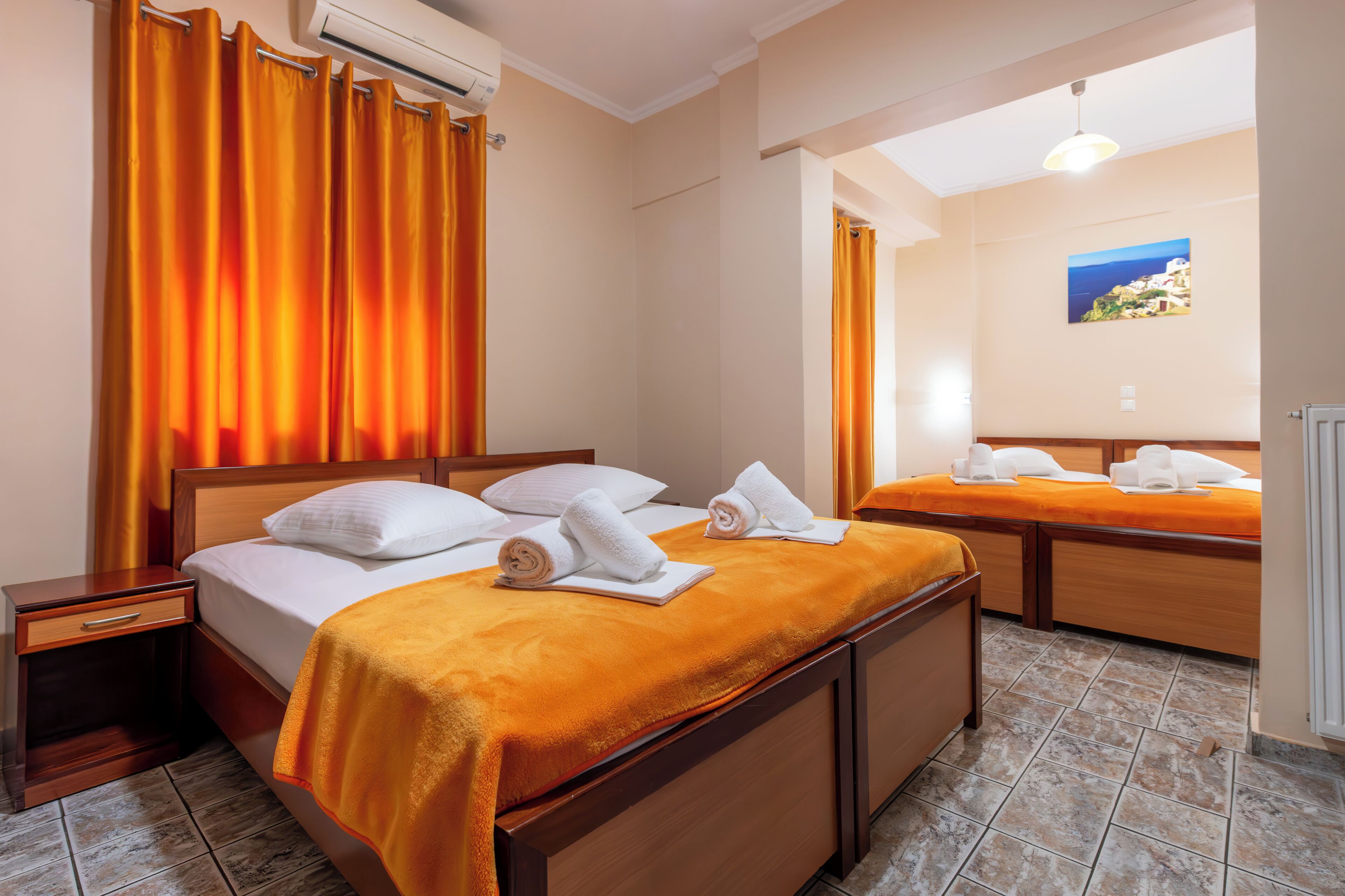 Ein Hotelzimmer mit zwei Betten, einem Holzkopfteil, einem Badezimmer mit Duschvorhang und einem Bild an der Wand.
