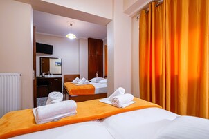 A hotel room with two beds, a desk, a mirror, and a television.