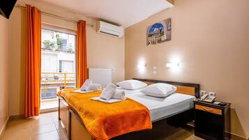 Een hotelkamer met twee bedden, een airconditioner, een nachtkastje met een telefoon en uitzicht op het balkon.