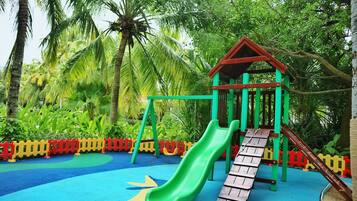 A playground with a slide, climbing structures, and a small shelter.