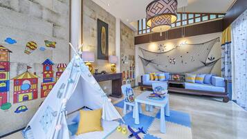 A child-friendly room with a play tent, colorful wall decorations, a sofa, and a hammock.