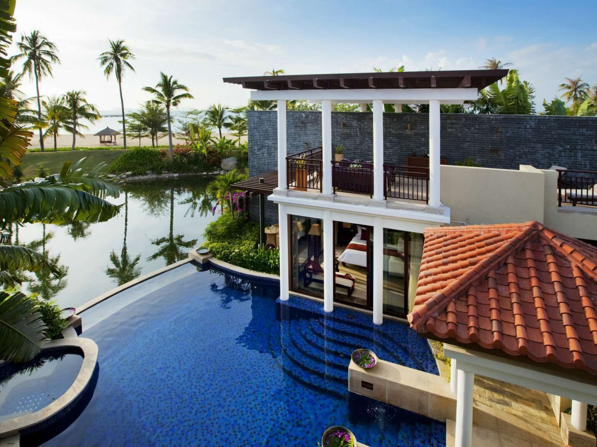 A resort with a swimming pool, a covered outdoor area, and a view of the beach.