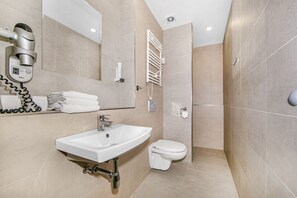 A modern bathroom with a sink, toilet, and a shower area.