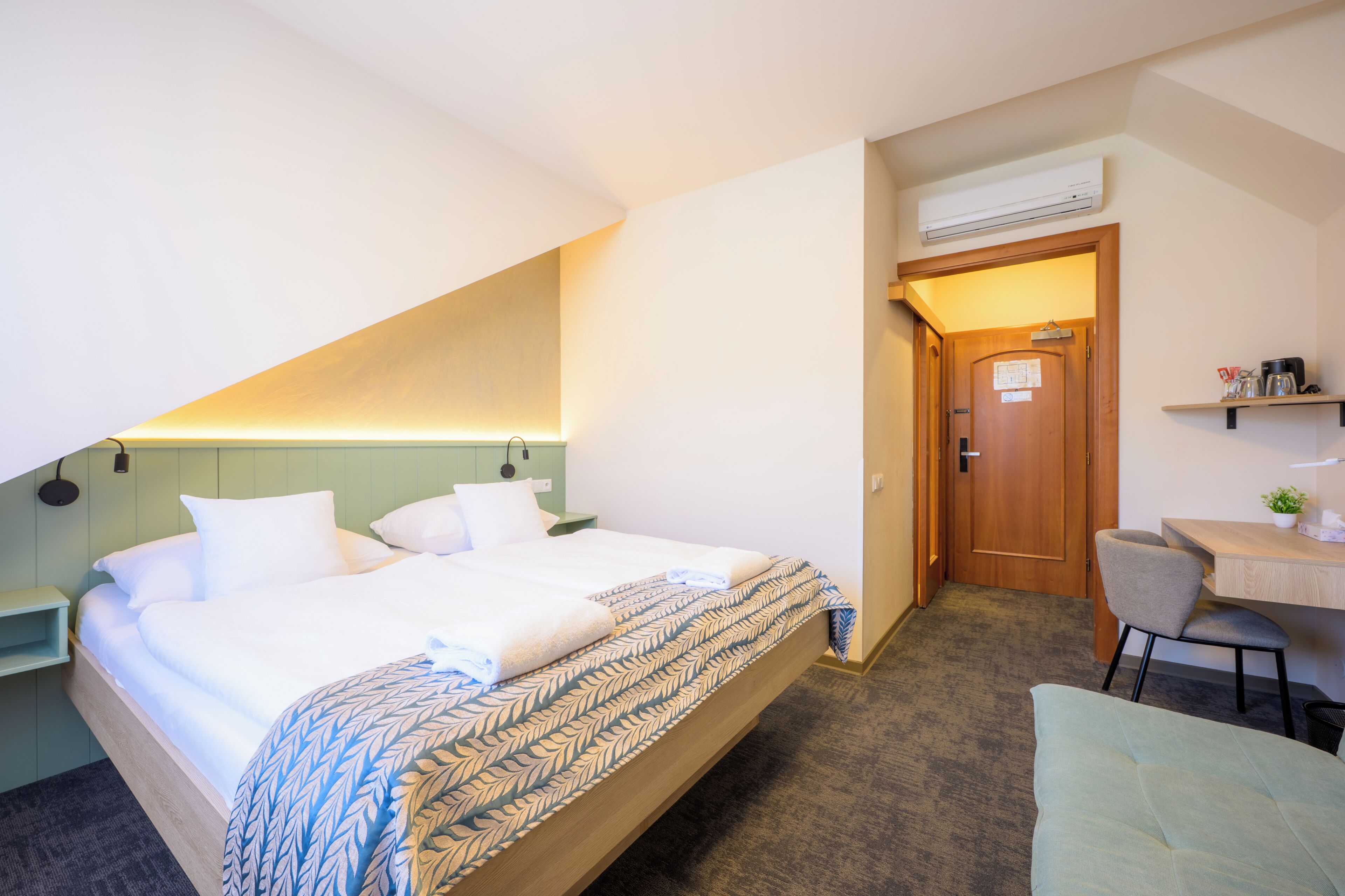 Une chambre d’hôtel équipée d’un lit, d’un bureau, d’une chaise et d’un appareil de climatisation.
