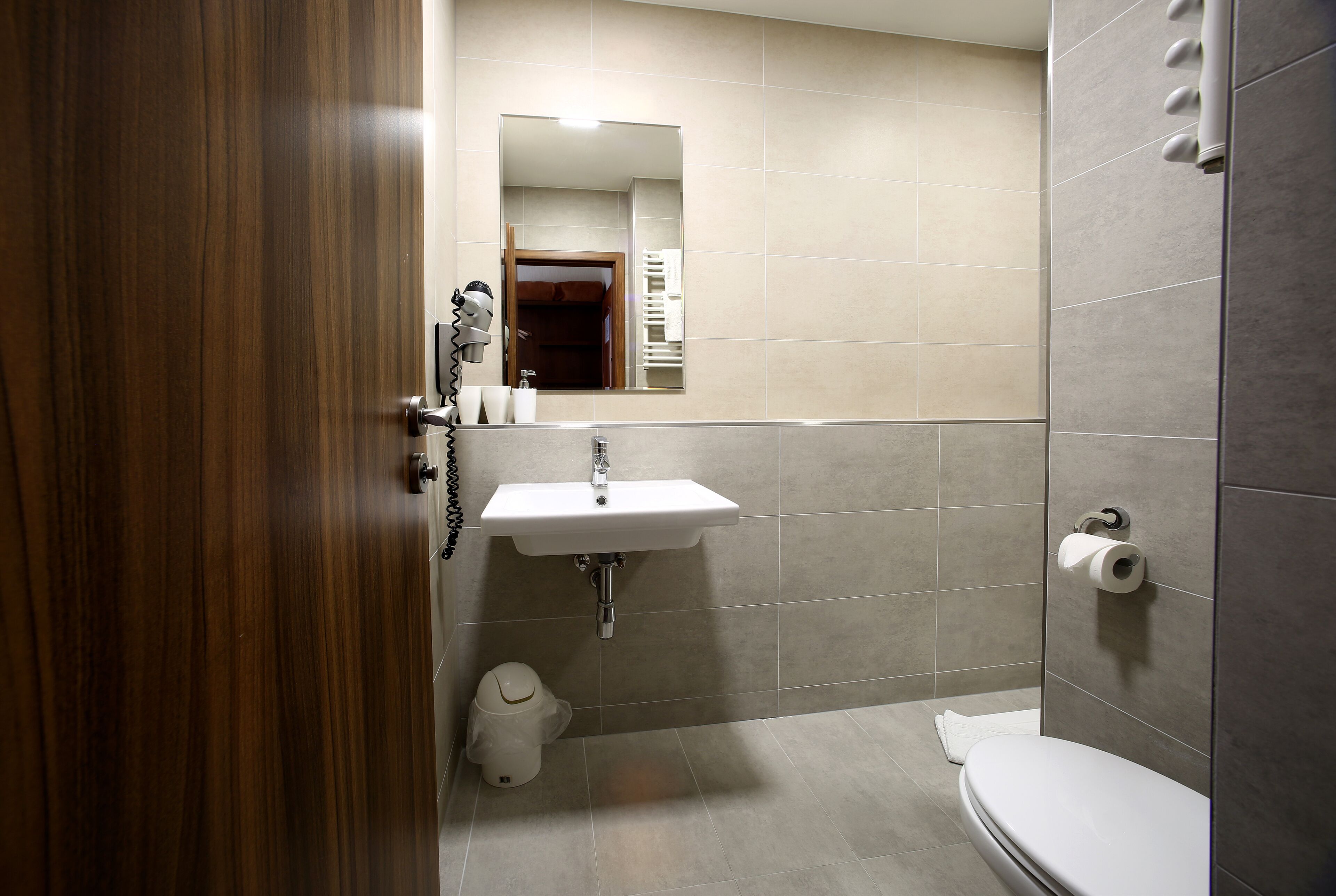 A bathroom with a wooden door, a sink, a toilet, and a shower area.