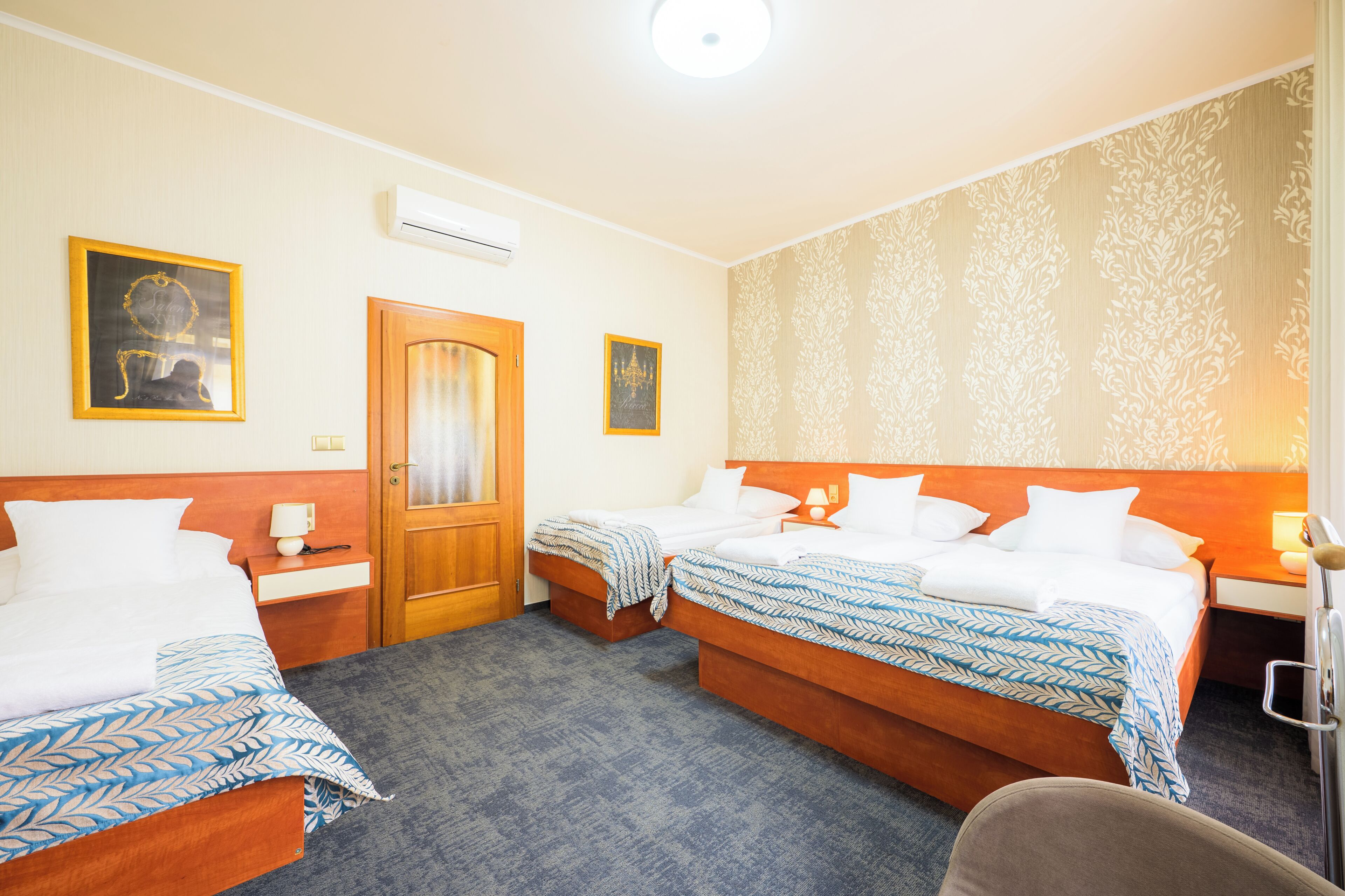 A hotel room with two beds, a wooden door, and a patterned wallpaper.