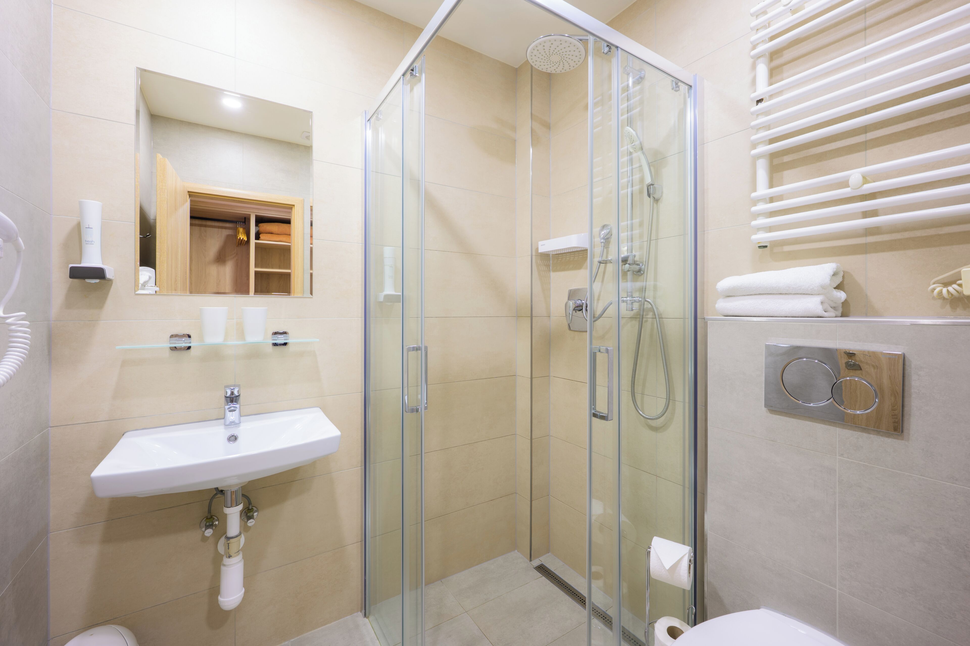 A modern bathroom with a glass-enclosed shower, a sink with a mirror, and a towel rack.