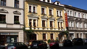 Un hôtel à la façade jaune, doté de nombreuses fenêtres et d’une enseigne rouge.
