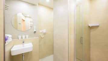 Un baño moderno con lavamanos, espejo y cabina de ducha de vidrio.