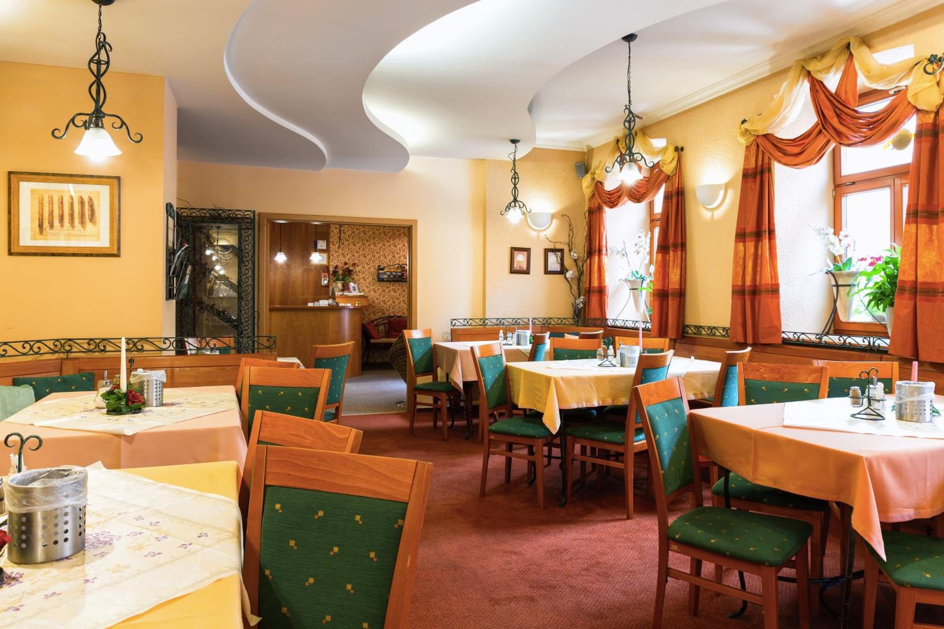 Um restaurante com várias mesas e cadeiras, um espaço com bancos de madeira e um teto decorativo.