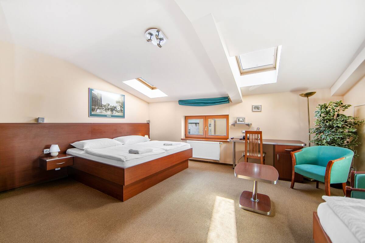 A hotel room with a bed, desk, chair, and a large window.