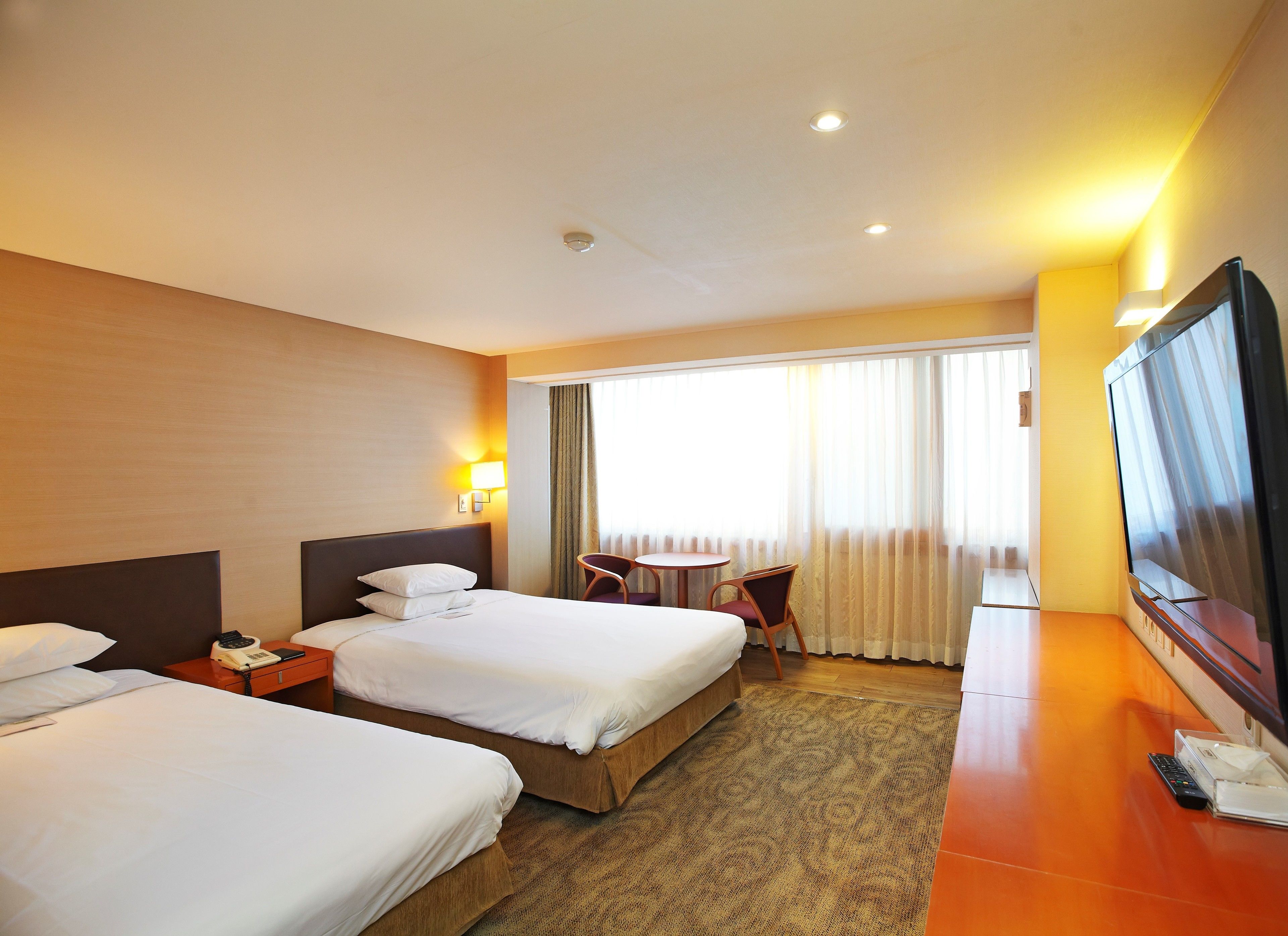 Une chambre d’hôtel avec deux lits, une télévision, un bureau et une chaise.