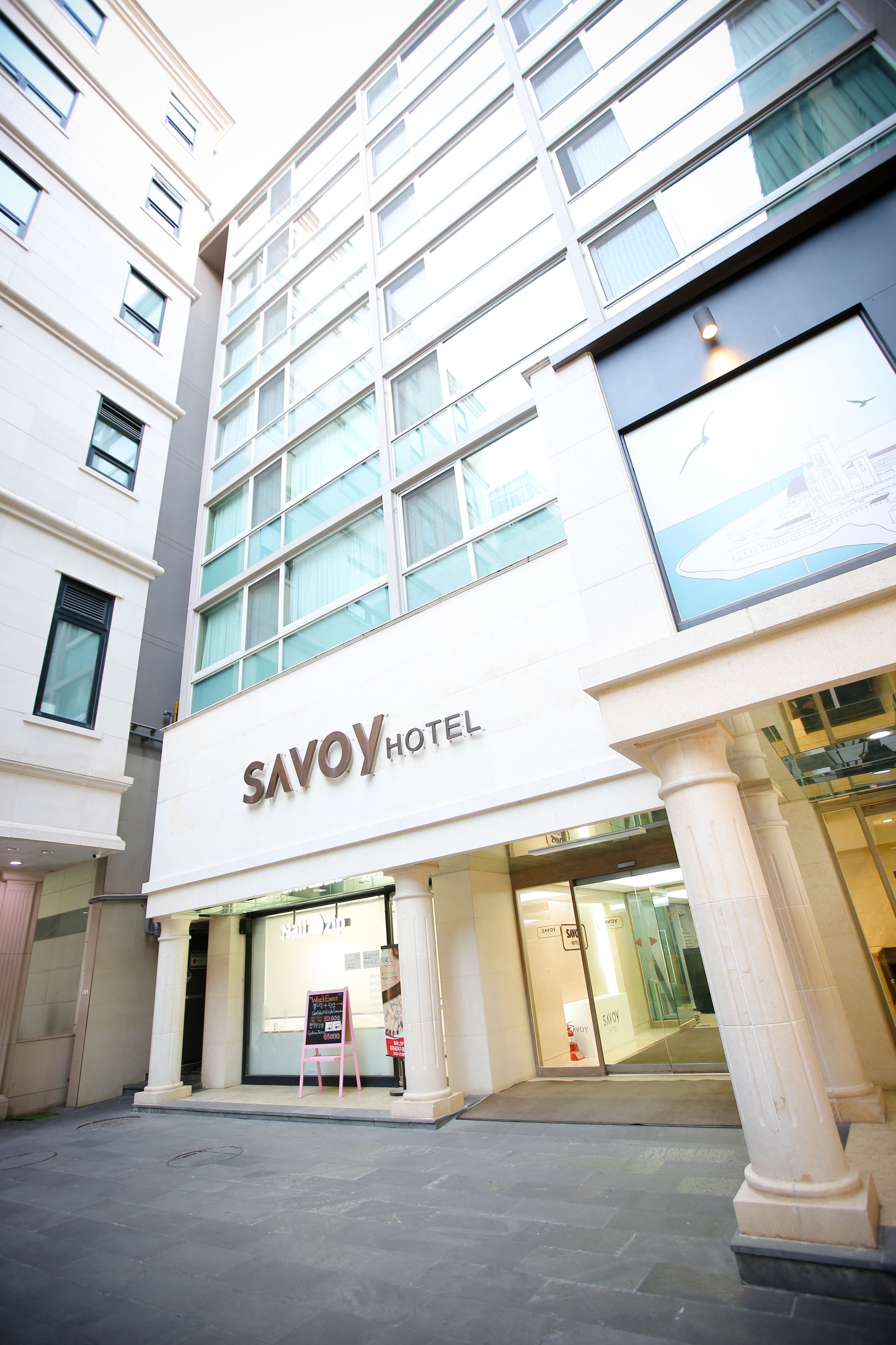 A modern hotel building with a prominent 'Savoy Hotel' sign.
