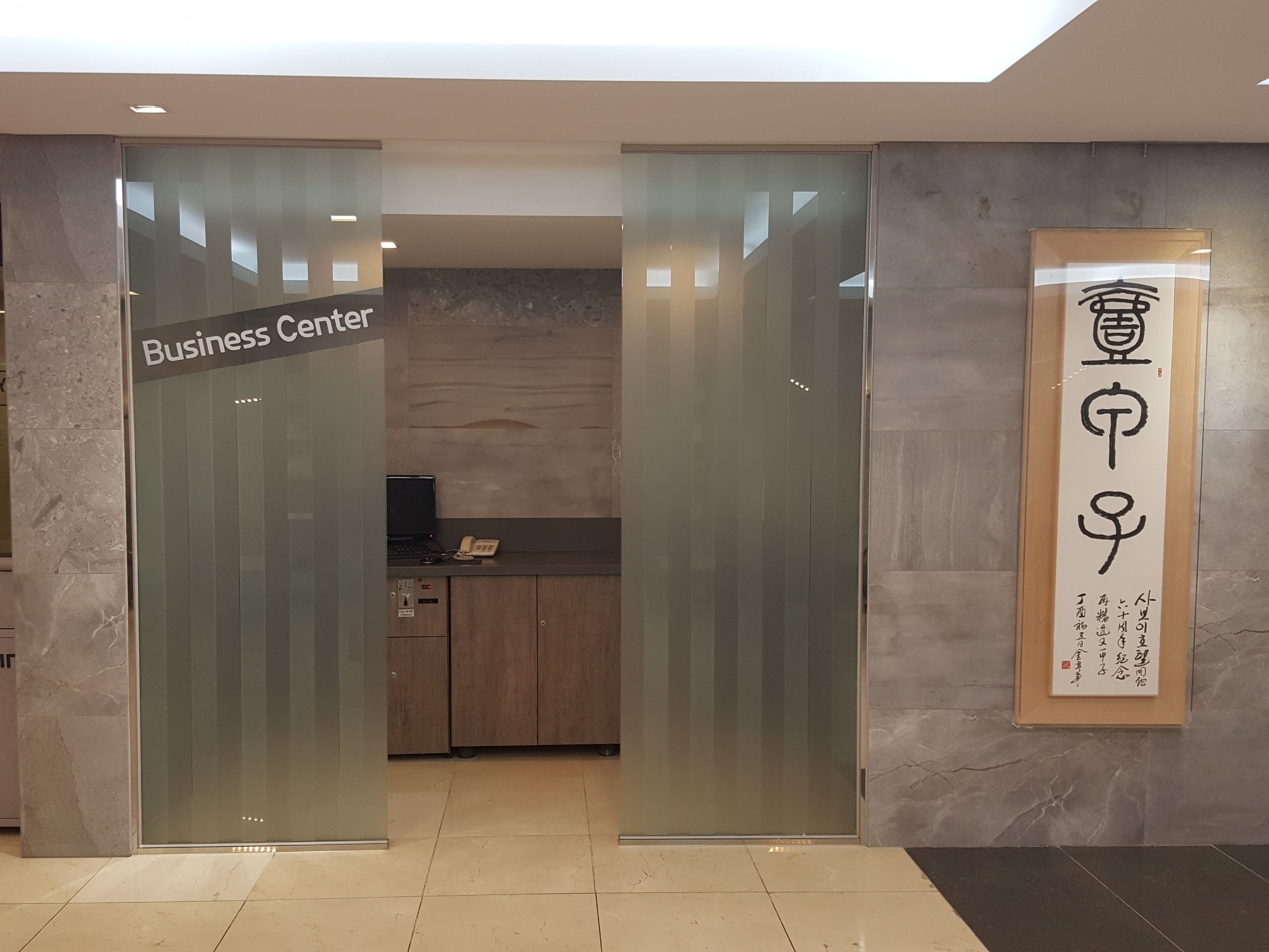 A business center with a reception desk, a computer, and a phone.
