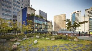 A hotel courtyard with stone pathways, grass, and scattered rocks. - Savoy Hotel (Seoul)