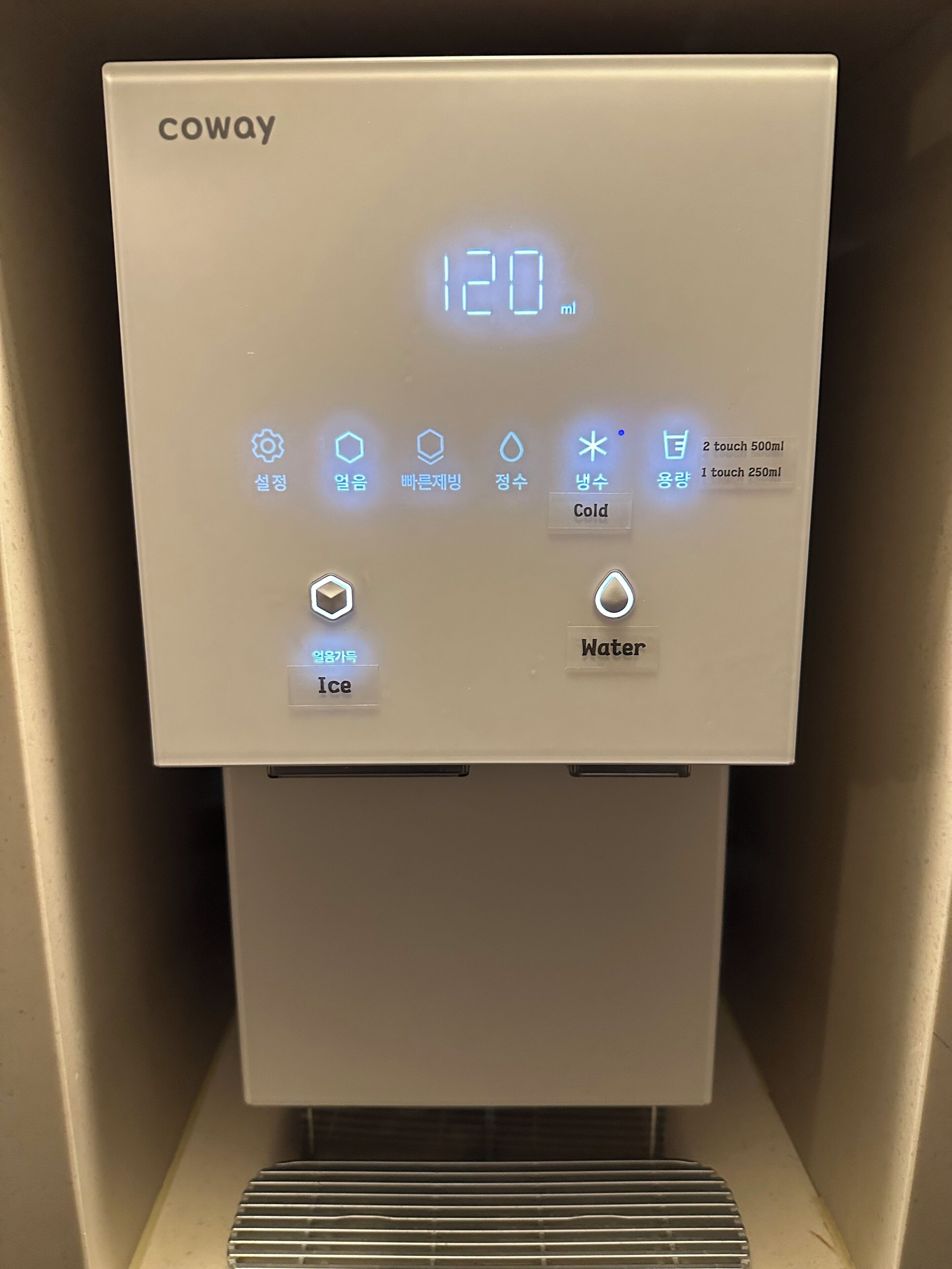 Ein Coway Wasserautomat mit digitaler Anzeige, die 120 ml sowie Optionen für Eis- und Wasserabgabe zeigt, einschließlich einer berührungslosen 500-ml-Auswahl.