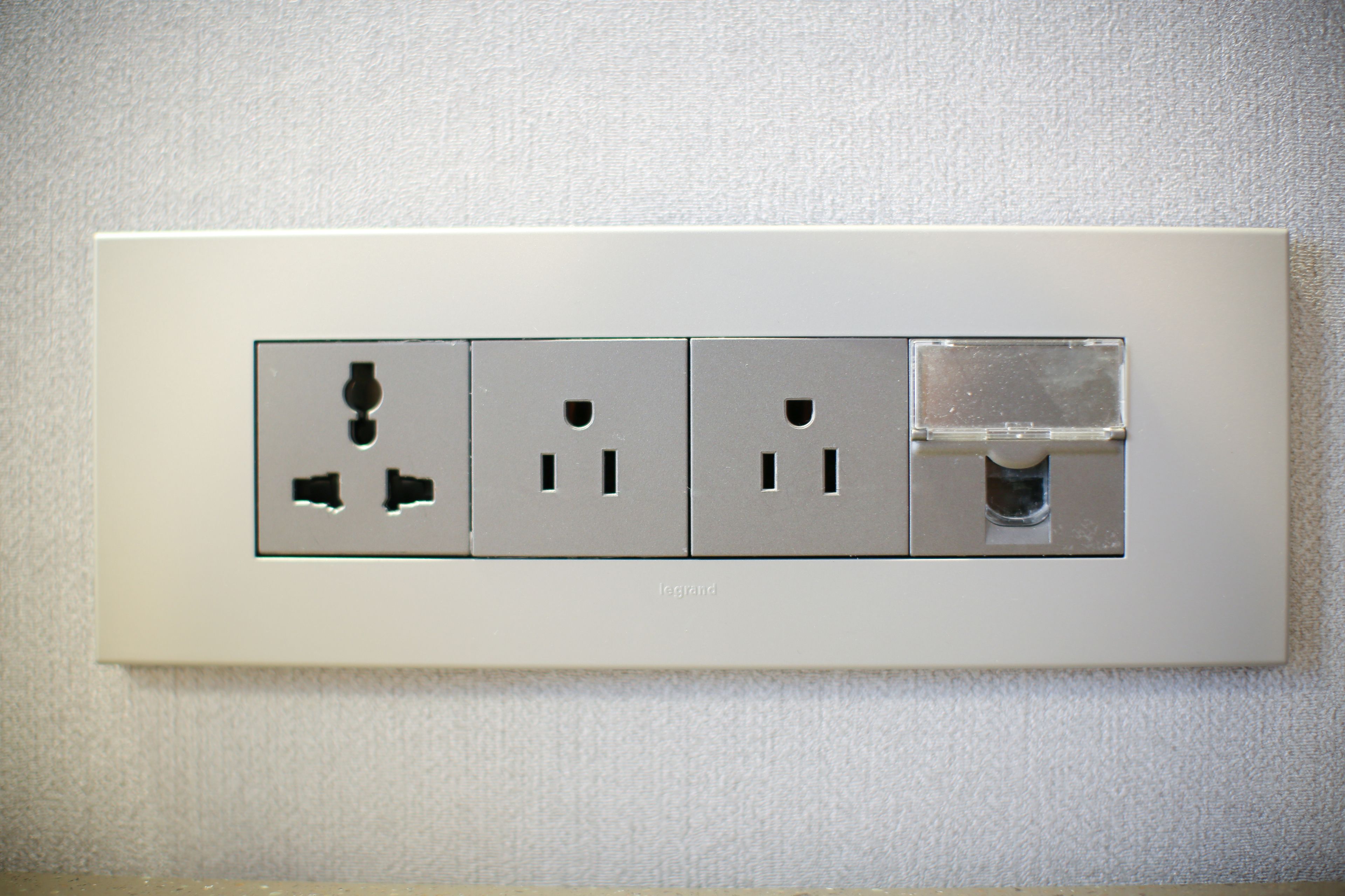Une prise électrique blanche dotée de quatre prises, dont un port USB, fixée sur un mur à texture.