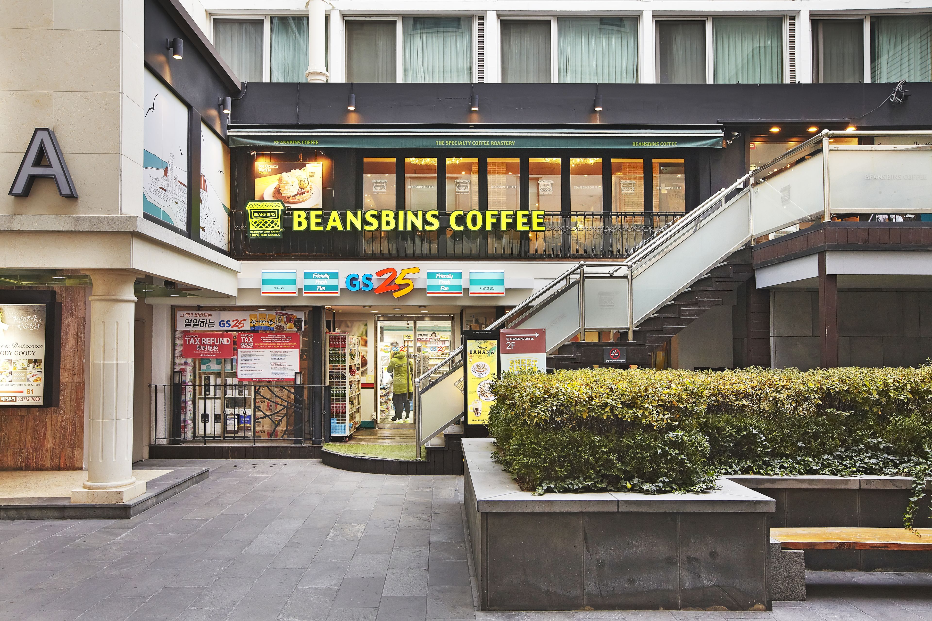 Un café appelé « Beansbins Coffee » avec un escalier menant à un étage supérieur.