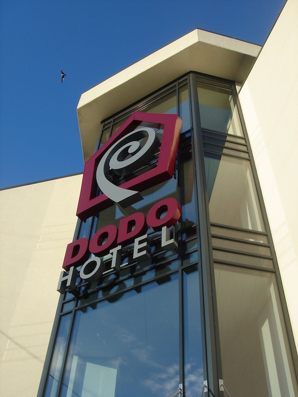 A Dodo Hotel sign on a building with a clear blue sky in the background.
