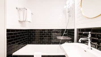 A modern bathroom with a white bathtub, a sink, and a mirror.