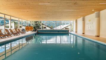 A swimming pool with lounge chairs and a view of the mountains.