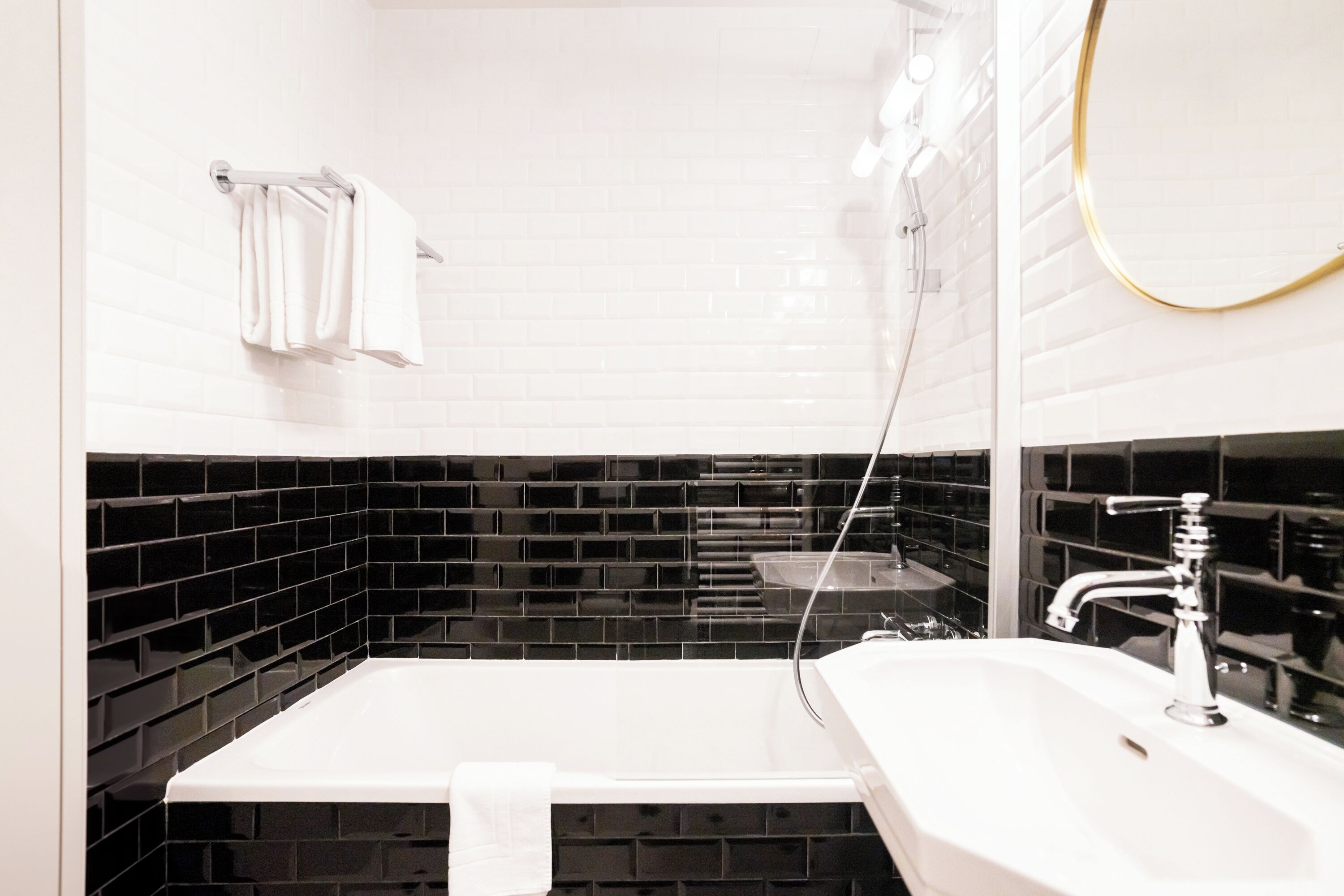 A bathroom with a white sink, a mirror, and black tiled walls.
