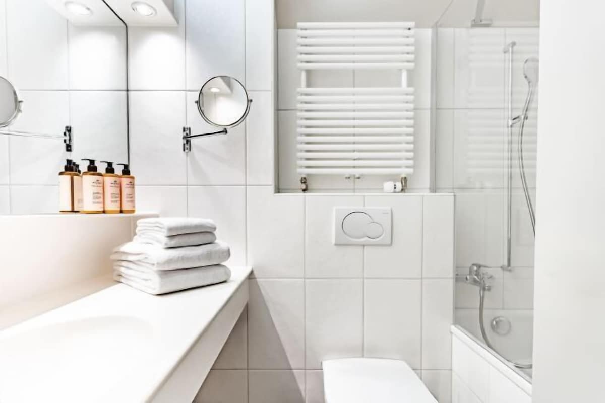 Een moderne badkamer met een wit wastafelmeubel, spiegel en douche.