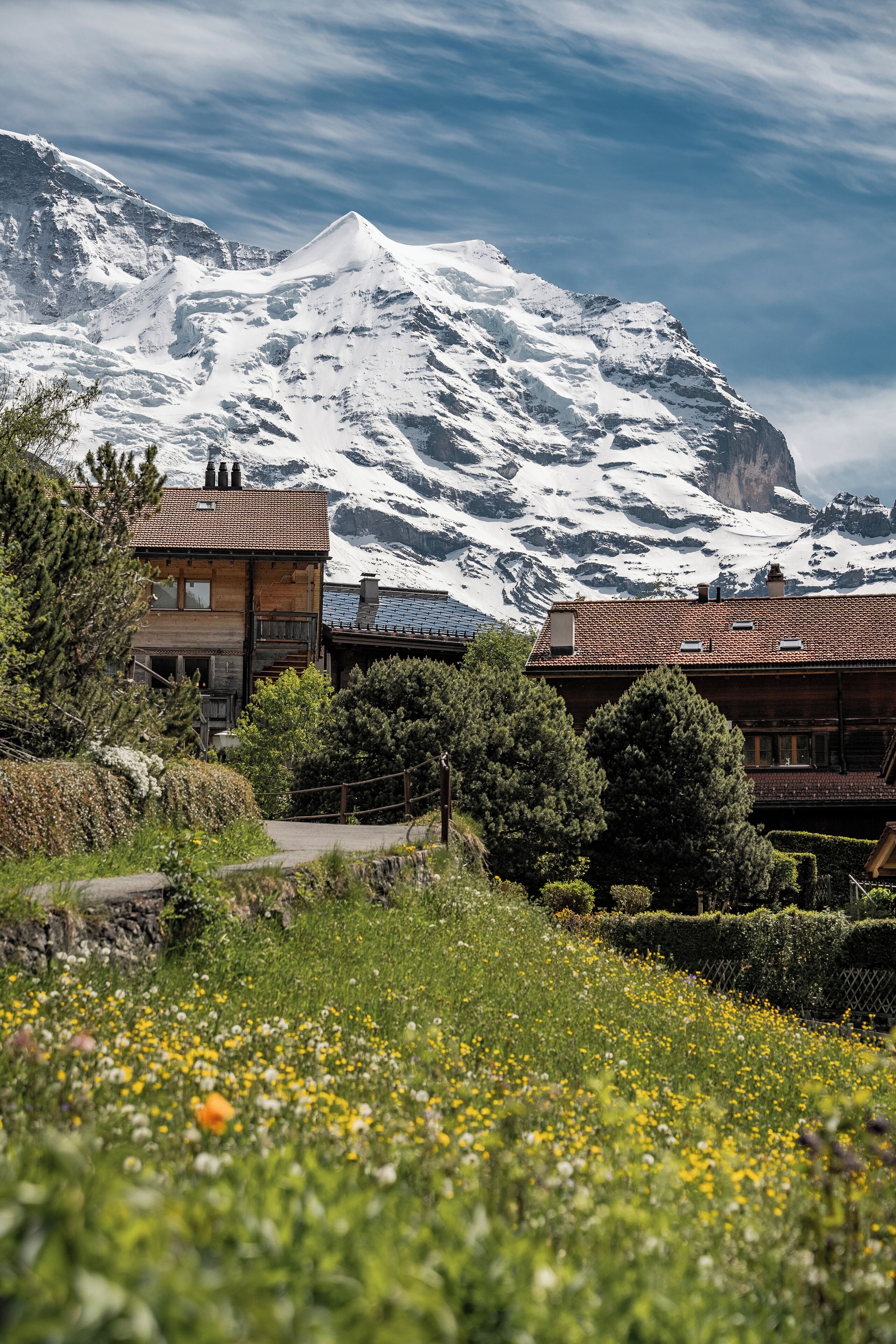A mountain lodge with a wooden exterior, a balcony, and a view of a snow-capped mountain.