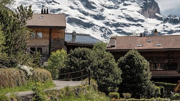 A mountain lodge with a wooden exterior, a balcony, and a view of a snow-capped mountain.