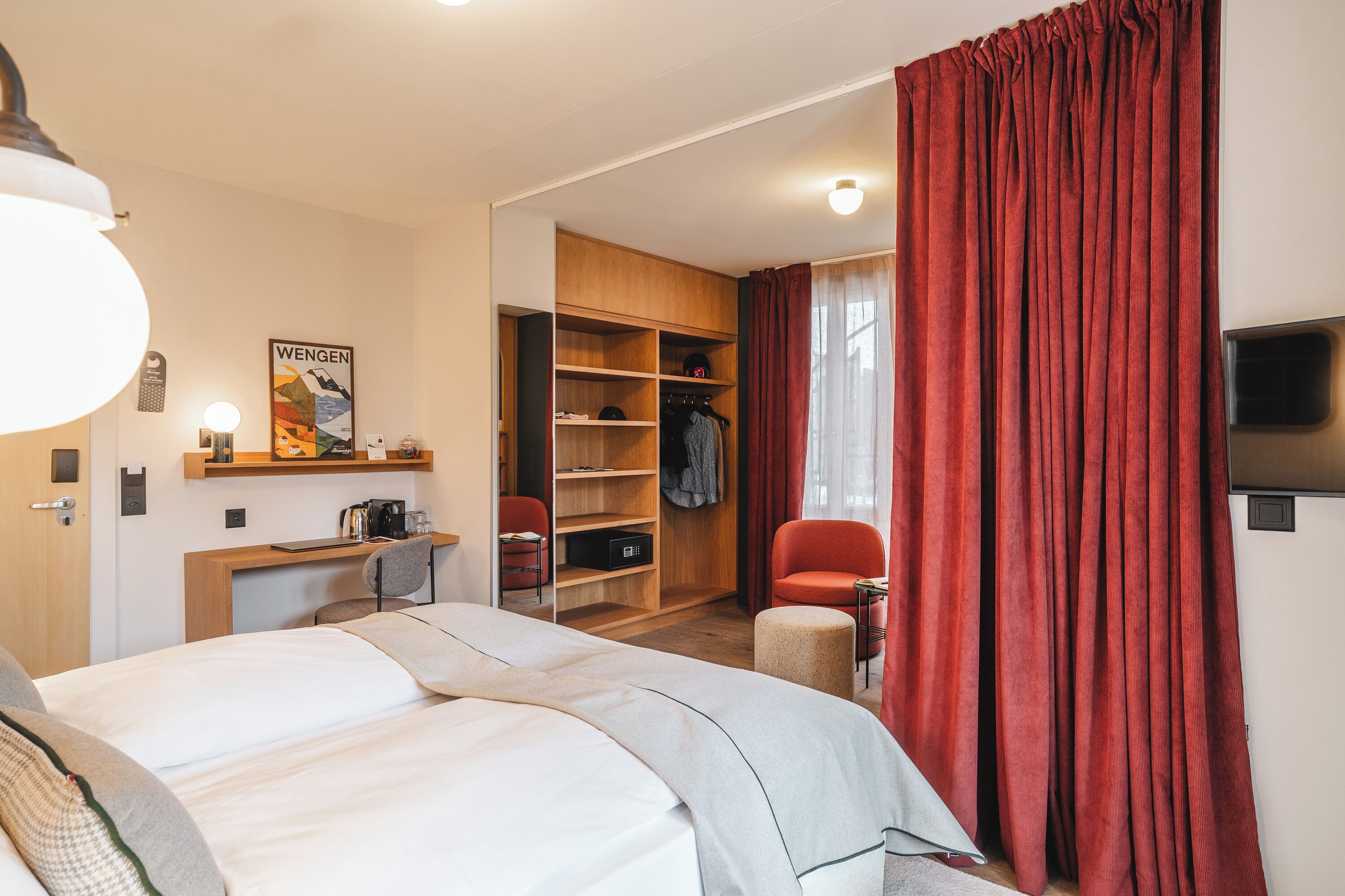 Una habitación de hotel con cama, escritorio, silla, armario y televisión.