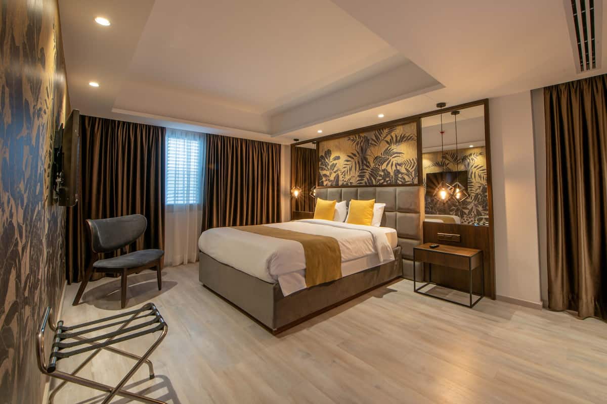 A modern hotel room with a large bed, a desk, and a chair.
