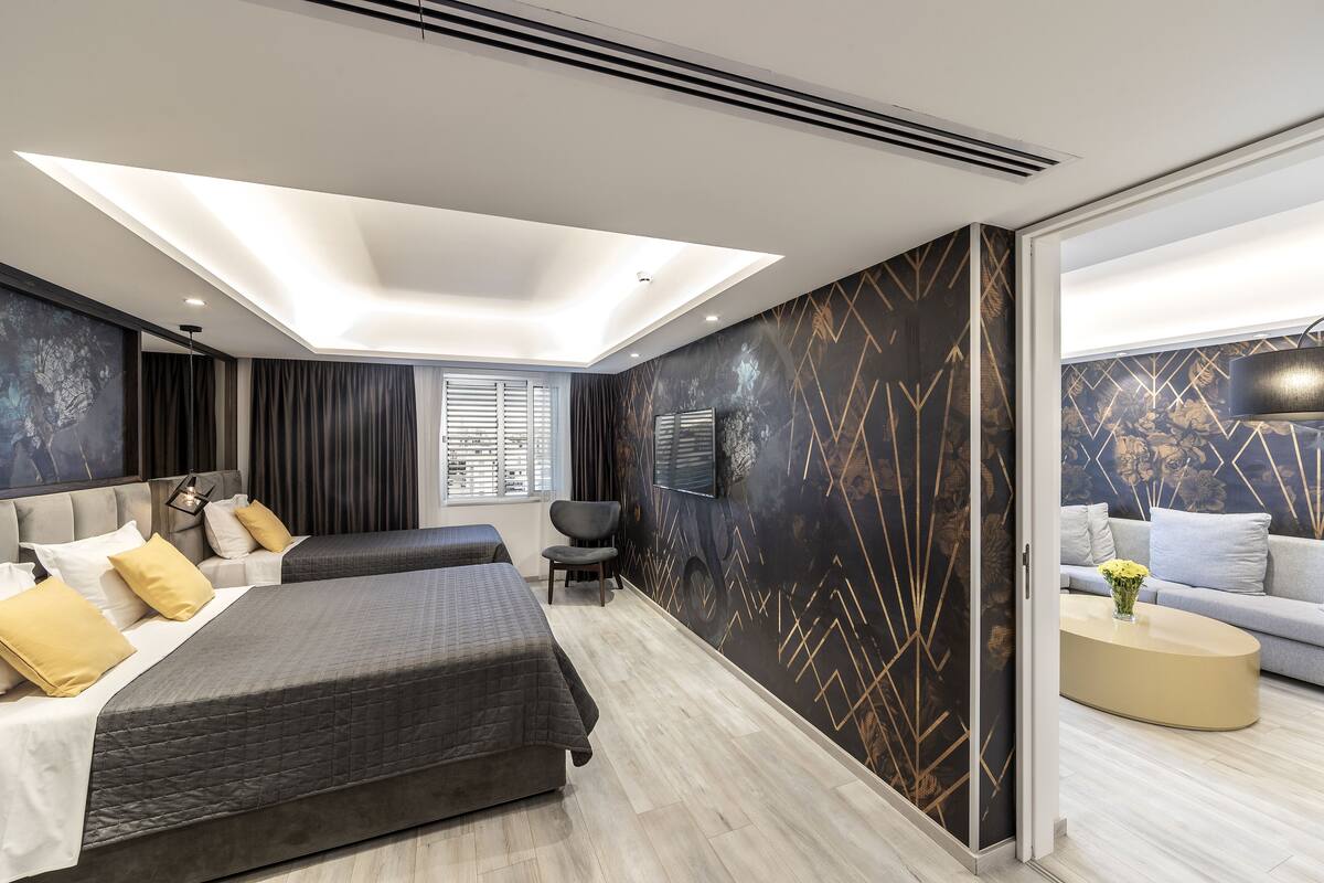 A modern hotel room with a large bed, a seating area, and a view of the city.