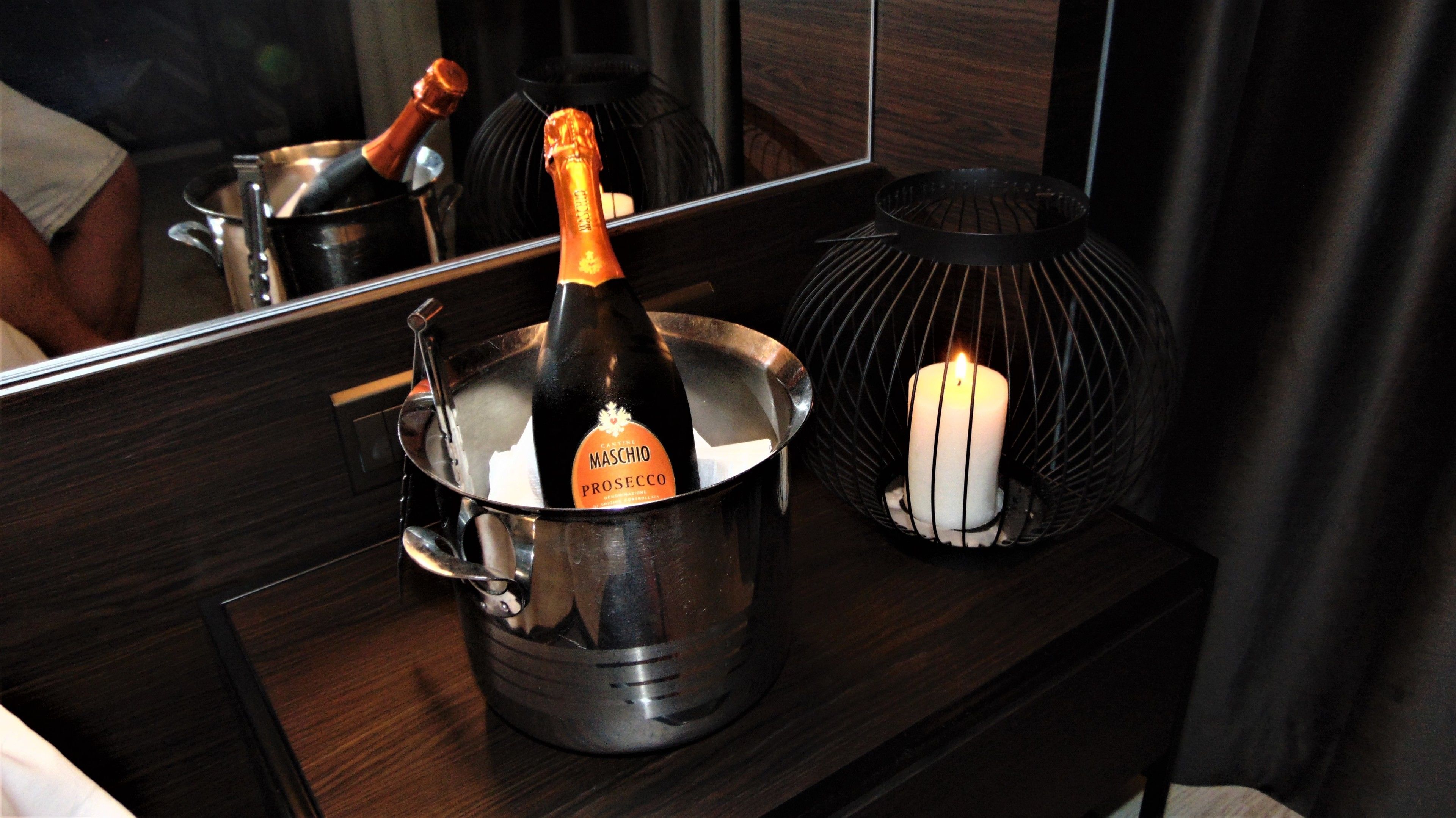 Ένα μπουκάλι αφρώδους κρασιού Maschio Prosecco μέσα σε ένα μεταλλικό κουβά, τοποθετημένο πάνω σε μια ξύλινη επιφάνεια.