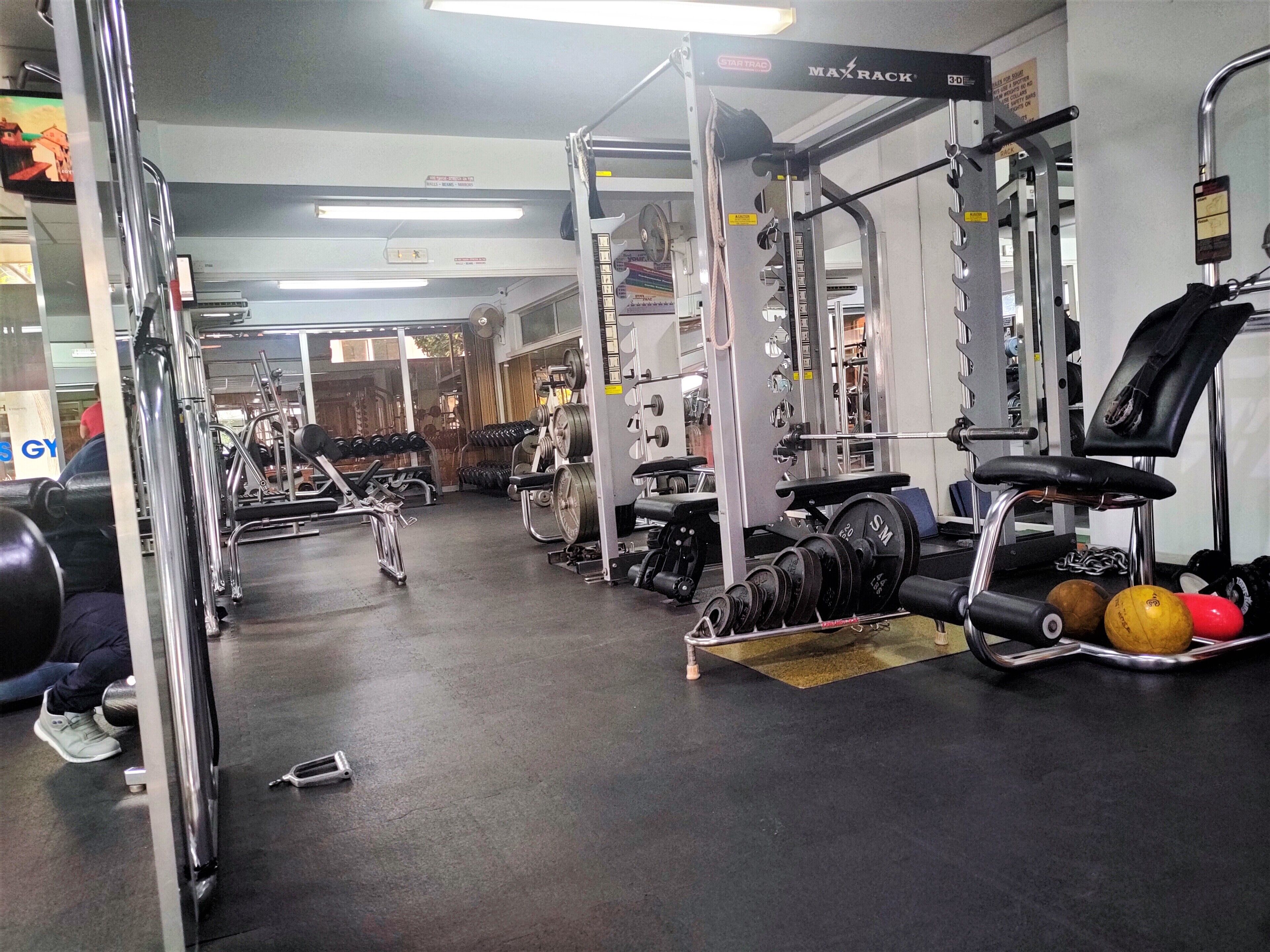 A gym with various exercise equipment, including dumbbells, a bench, and a squat rack.