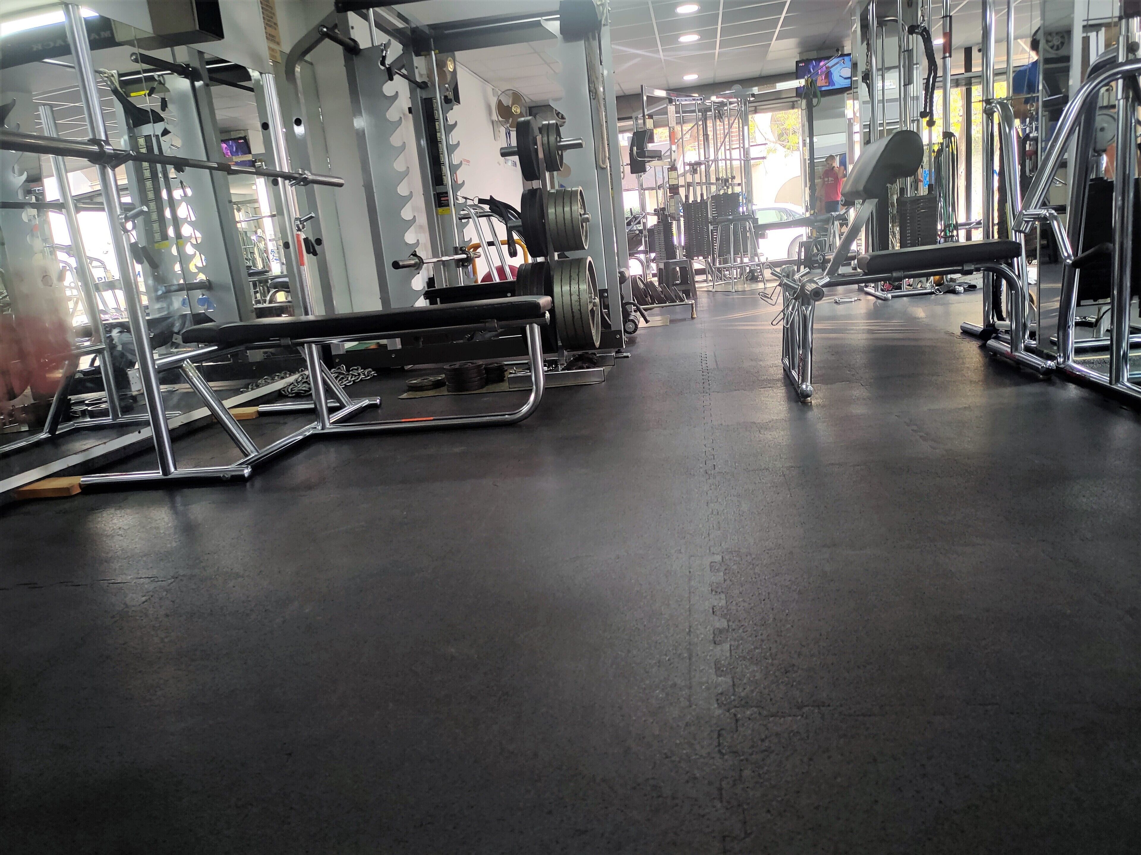 Et fitnesscenter med forskellig træningsudstyr, herunder vægtmaskiner og håndvægte.
