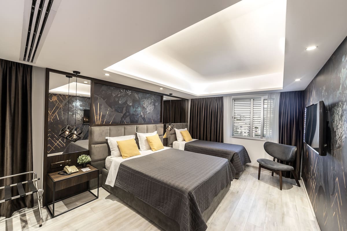 A modern bedroom with two beds, a bedside table with a lamp, a chair, and a large mirror.