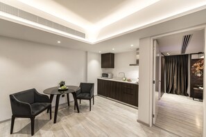 A modern kitchen with dark cabinetry, a microwave, and a dining area with two chairs and a table.