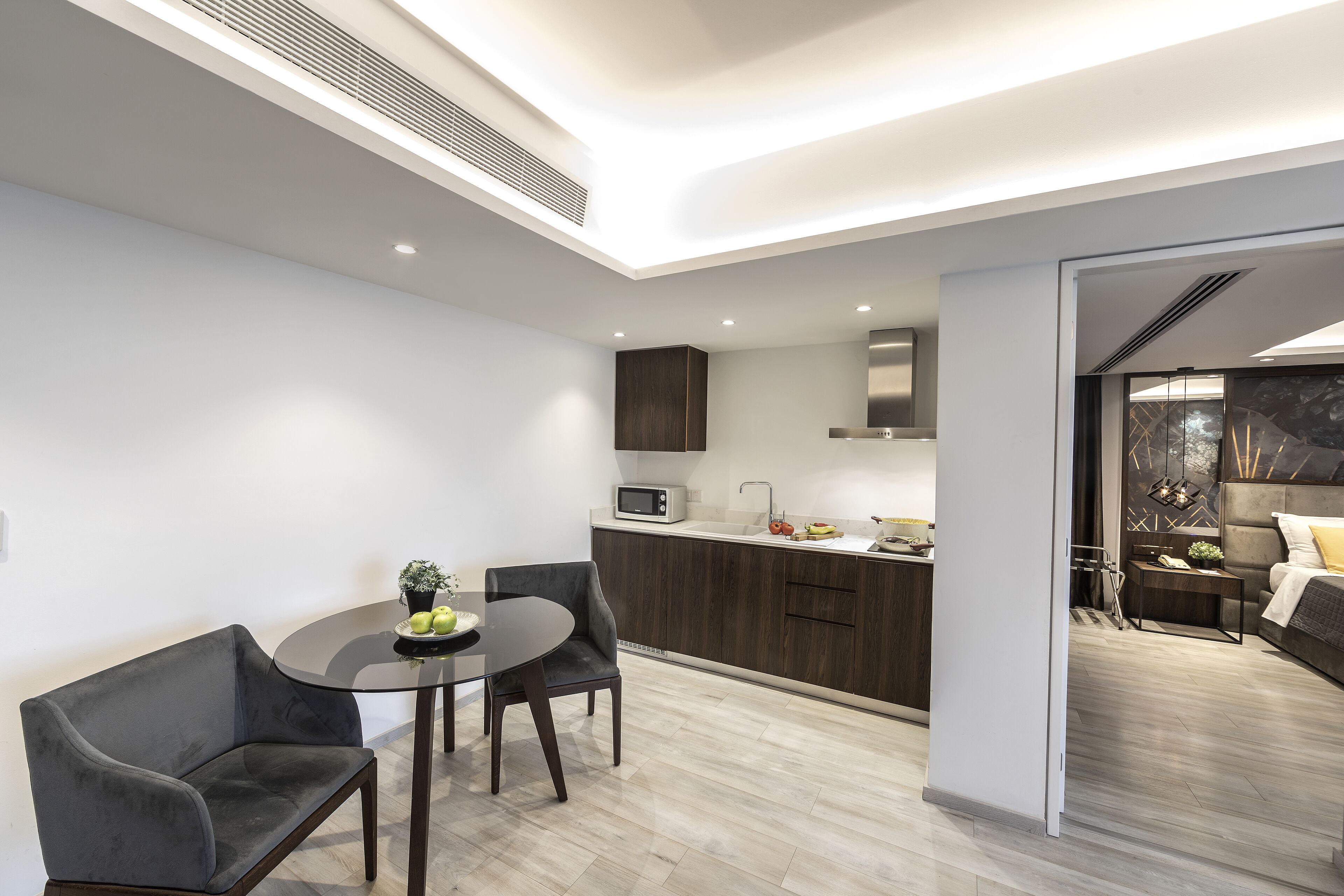 A modern kitchen with dark wood cabinets, a microwave, and a dining area with a table and two chairs.