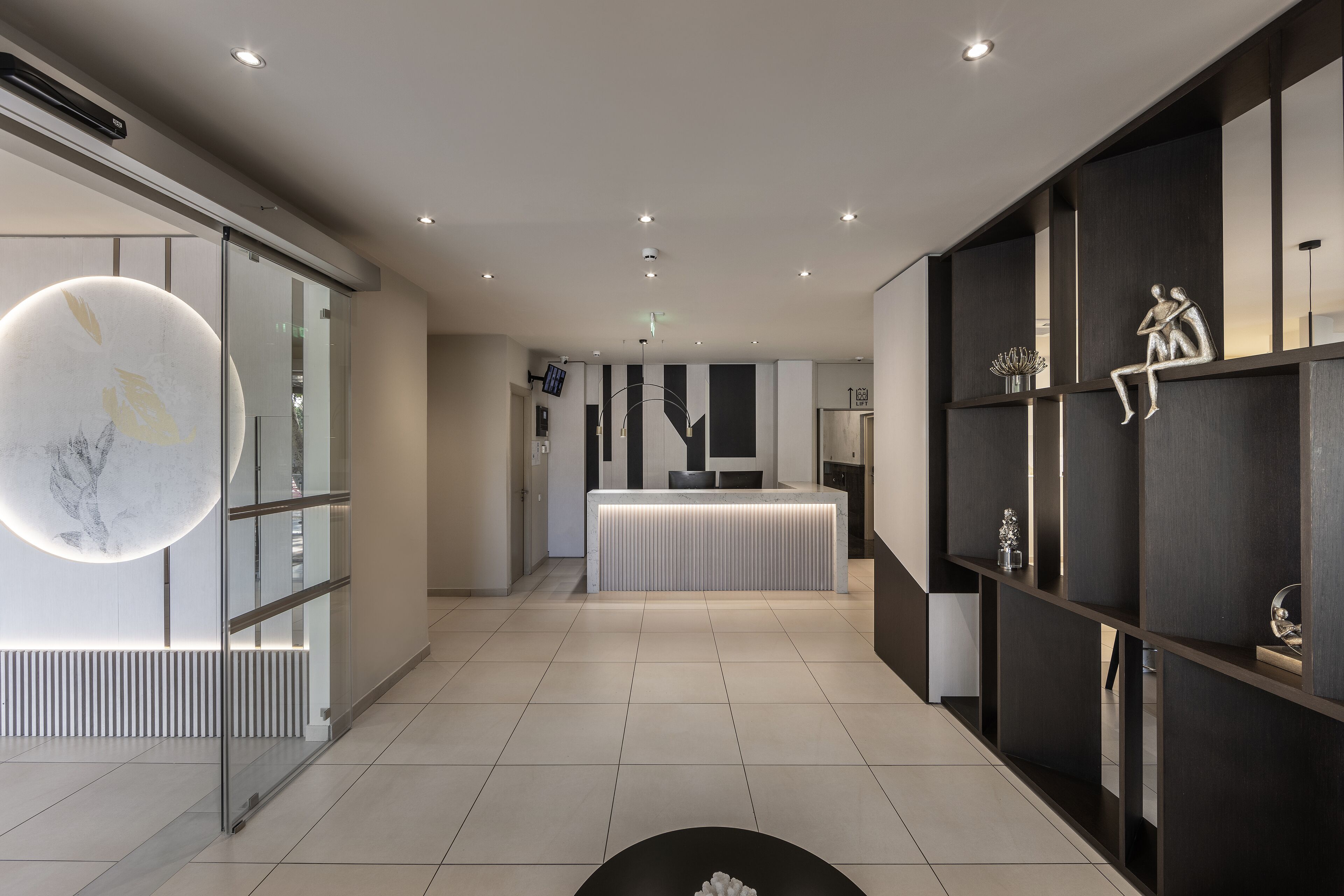 A modern hotel lobby with a reception desk, glass partitions, and minimalist decor.