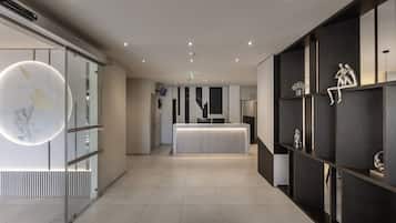 A modern hotel lobby with a reception desk, glass partitions, and minimalist decor.