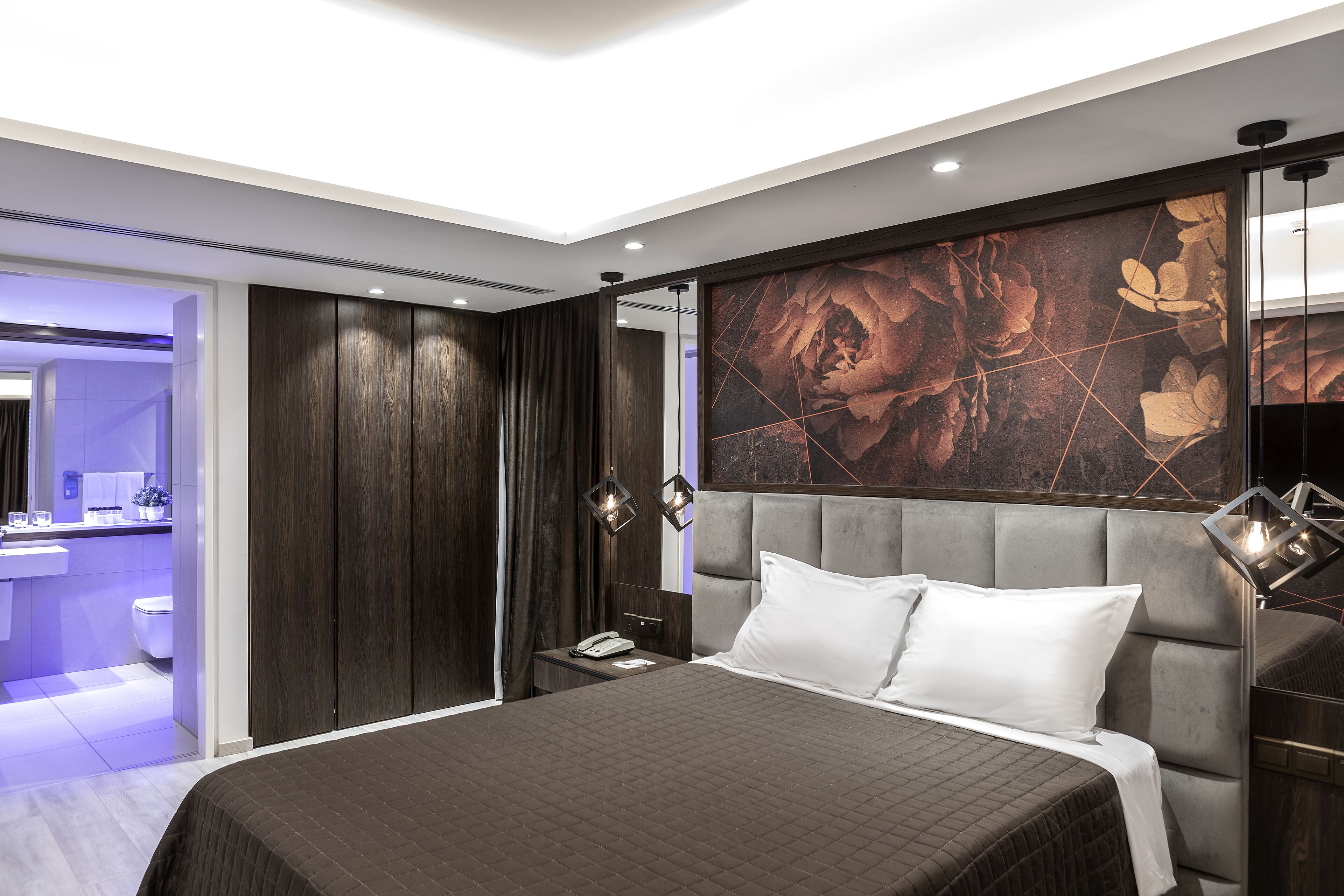 A modern bedroom with a large bed, a vanity, and a bathroom.