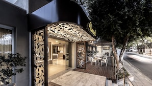 Un bâtiment moderne doté d’une entrée en verre, d’une terrasse en bois et d’une enseigne sur laquelle on peut lire « Aloft ».