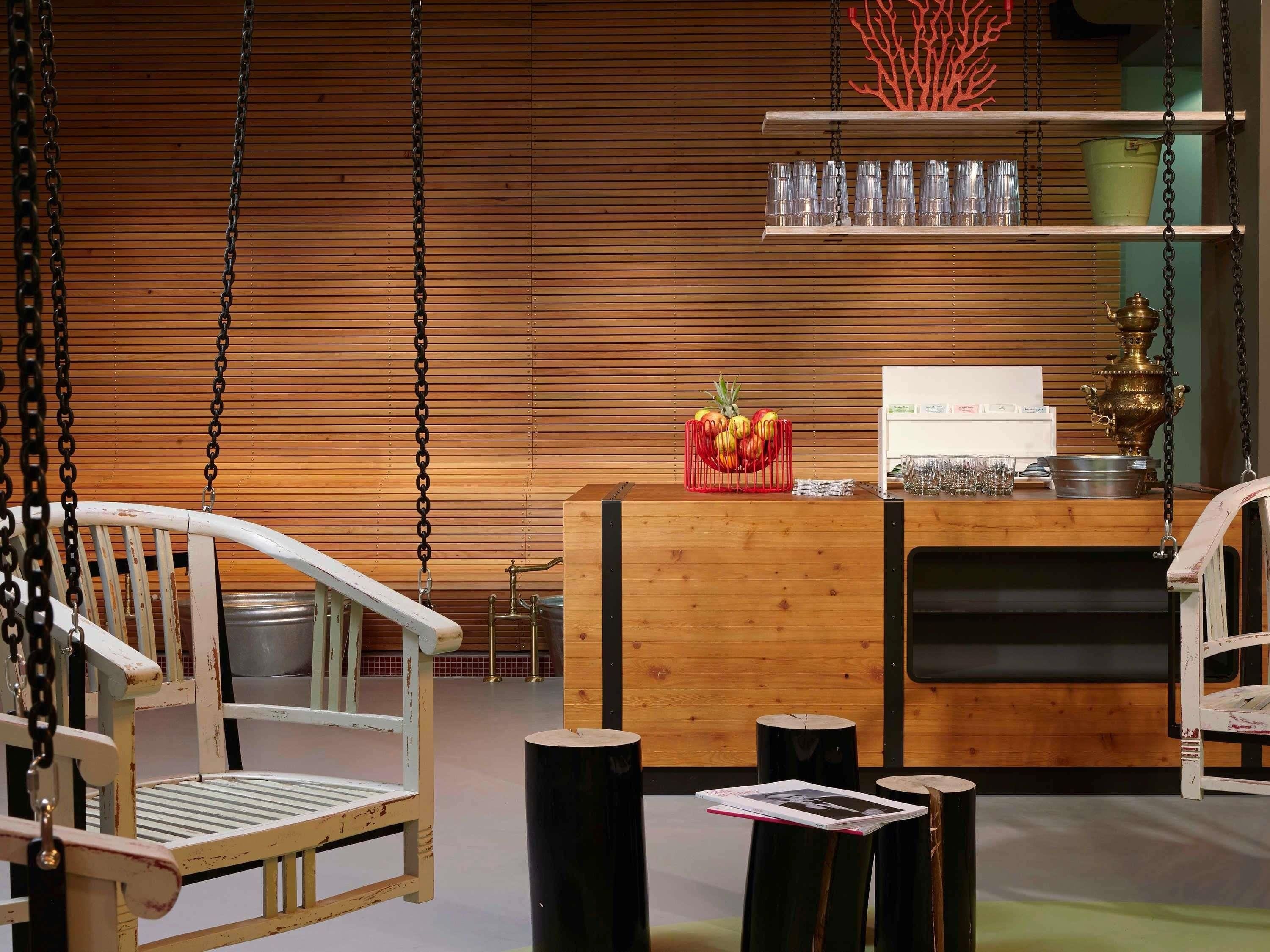 A wooden reception desk with a hanging chair, a shelf with glasses, and a decorative red coral.
