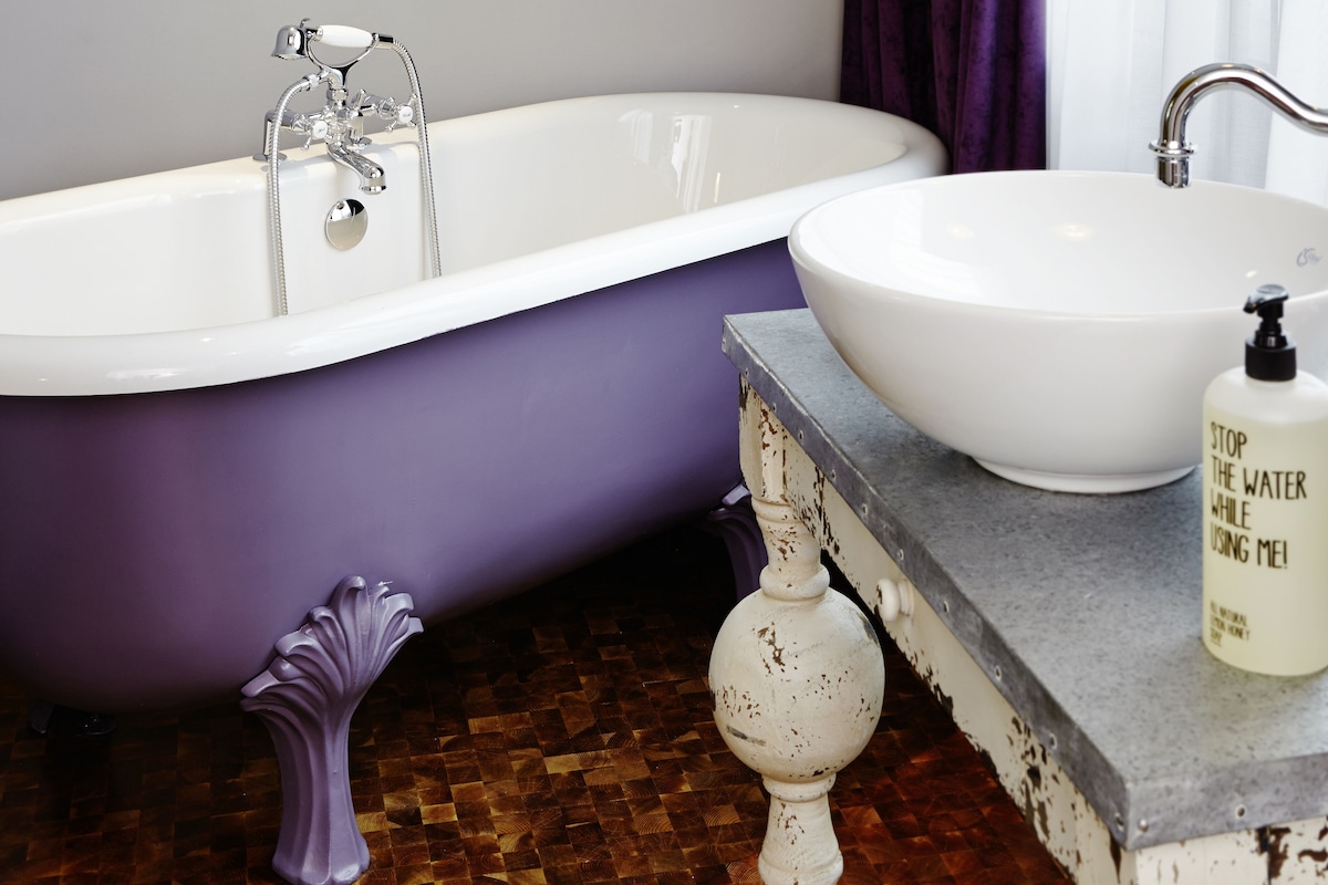A bathroom with a white bathtub, a white sink, and a bottle of hand soap on the countertop.