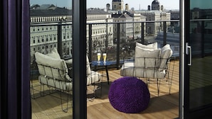 Een balkon met uitzicht op historische gebouwen, een tafel met drankjes en comfortabele zitplaatsen.