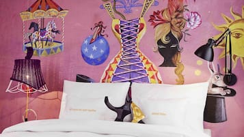 Een bed met witte beddengoed en twee kussens, waarvan één met een zwart-wit hondendesign en de ander met tekst.