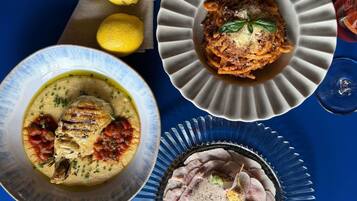 Una mesa con tres platos: una sopa cremosa con hierbas, un plato de pasta con carne y un plato de carne en rodajas con salsa cremosa.